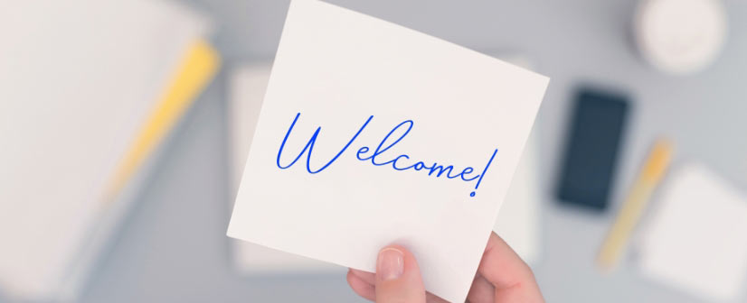 close up of a hand holding a piece of paper that says Welcome